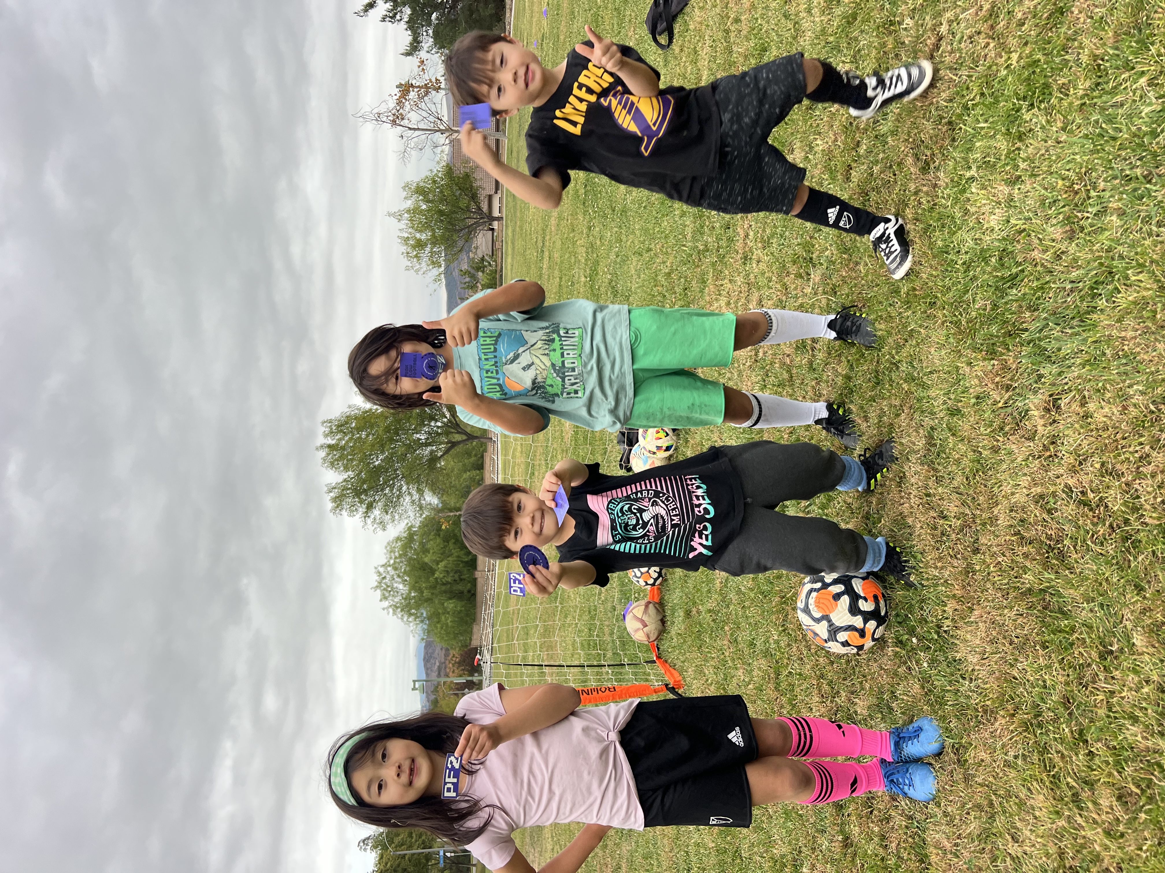 Young players holding Peak Flow Football stickers on the field